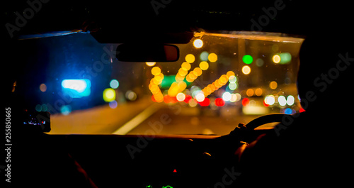 Selective focus of man driving a car at night. View from inside the car.