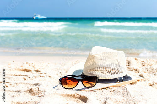 Close up straw hat and sunglasses on tropical beach and white sandy background. Summer vacation concept. traveling and relax.