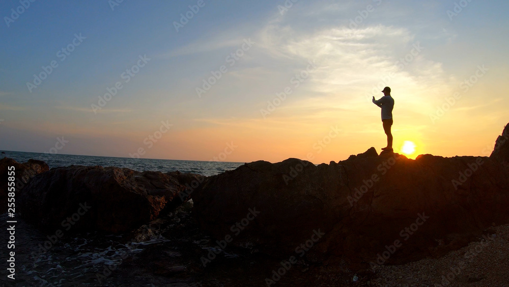 Silhouette of the man selfie in the sea at sunset