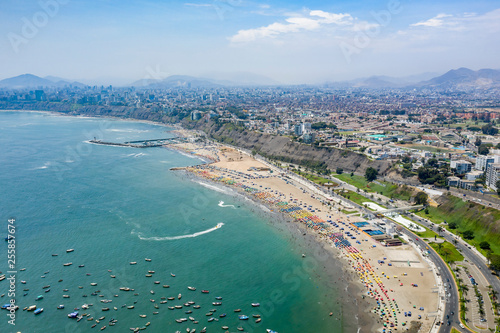 Lima, Peru - March 17 2019: Aerial view of Agua Dulce beach in the district of Chorrillos. Lima's coastal shoreline with blue ocean. Summer day, people relaxing having fun. © MyriamB