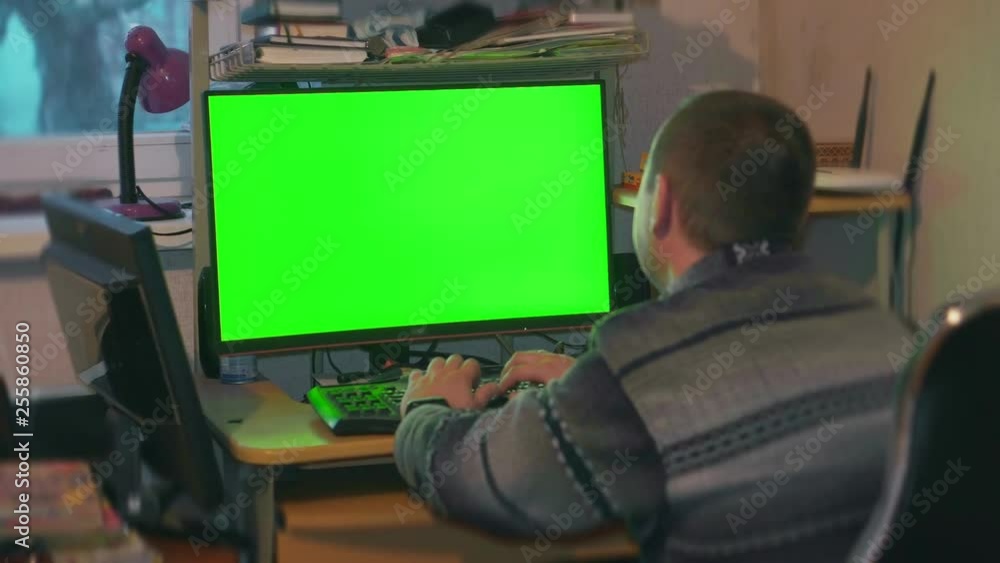 A man in a shirt and pants is watching a monitor screen with a green color A man in a shirt and pants is watching a monitor screen with a green color
