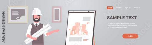 man architect in helmet holding blueprints in rolls engineer showing new drawing building on easel board panning project concept house blueprint horizontal portrait copy space