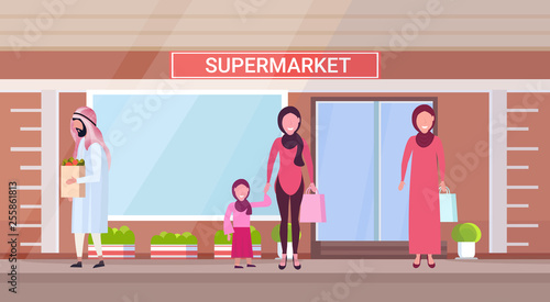 arab people in traditional clothes holding shopping bags with groceries arabic characters standing outdoor modern grocery shop supermarket exterior horizontal