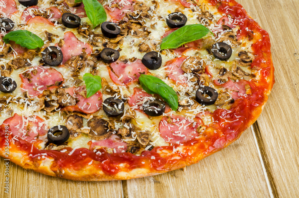 Pizza with ham, mushrooms and olives on wooden surface. Pizza with ham, mushrooms and olives on wooden surface.