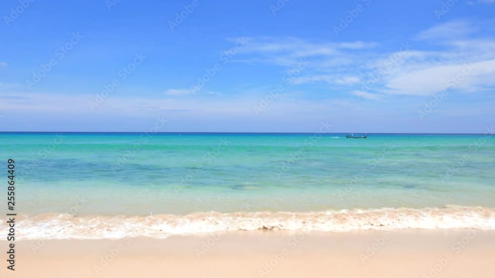 On a hot, sunny day, calm, gentle waves wash up on a sandy beach, as a small boat passes along the horizon On a hot, sunny day, calm, gentle waves wash up on a sandy beach, as a small boat passes along the horizon
