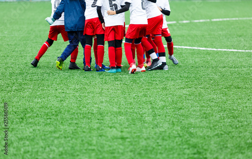 Football training, soccer for kids. Boy footballers in white and red sportswear stand together on soccer field. Training, active lifestyle, sport, children activity concept 