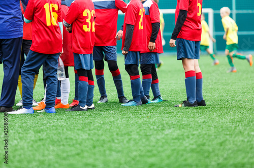 Football training, soccer for kids. Boy footballers in white and red sportswear stand together on soccer field. Training, active lifestyle, sport, children activity concept 