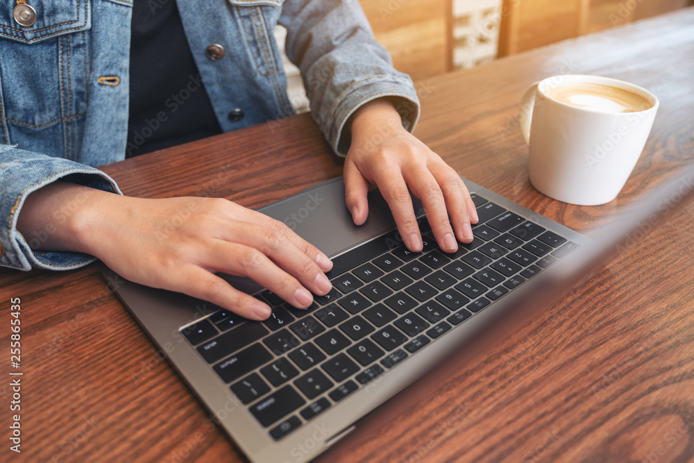 Closeup image of woman's hands using and typing on laptop keyboard on the table Closeup image of woman's hands using and typing on laptop keyboard on the table