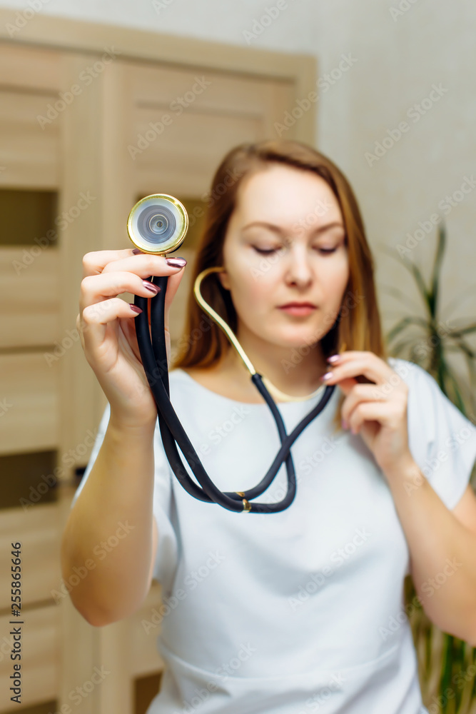 Close up portrait of doctor with stethoscope in ear. A female doctor with a stethoscope listening. Physician listening to empty space with stethoscope. Close up portrait of doctor with stethoscope in ear. A female doctor with a stethoscope listening. Physician listening to empty space with stethoscope.