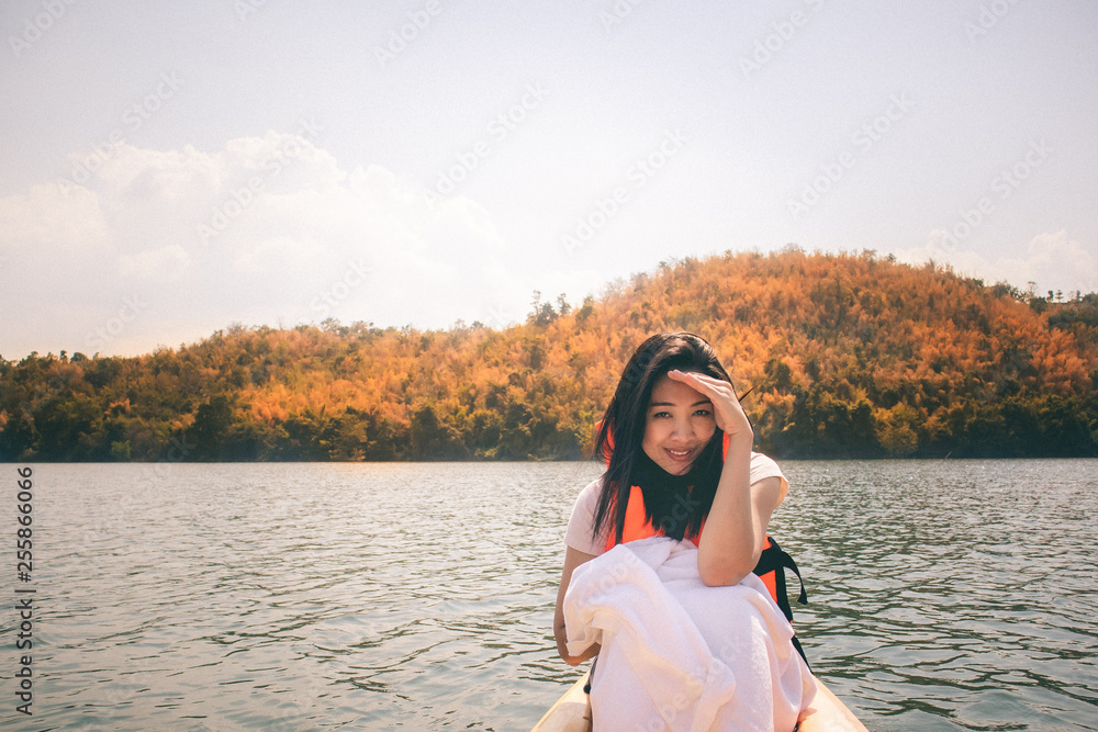 Woman wear vivid orange life jacket or life vest on kayak in the lake.