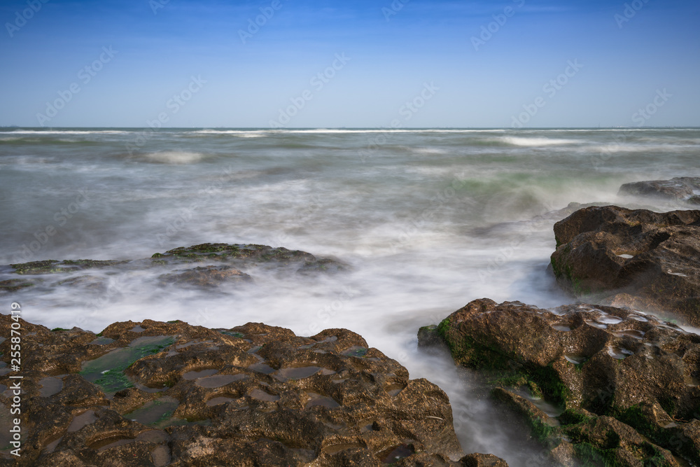 Colorful sea shore with green algae, long exposure water