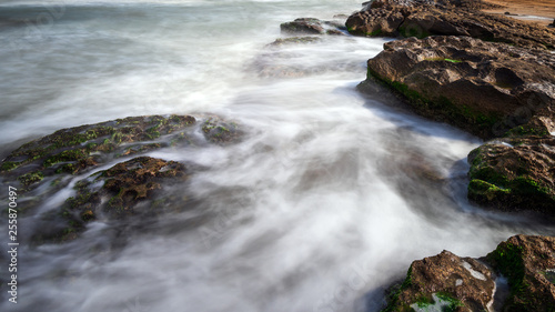 Colorful sea shore with green algae, long exposure water