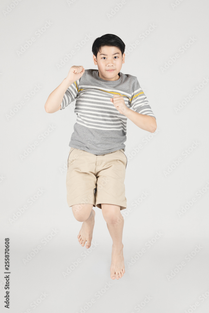 Asian funny child boy jumping on gray background.