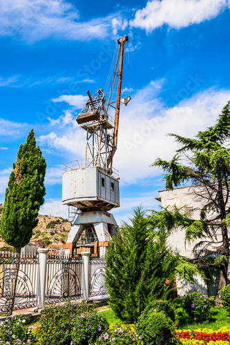 Port crane on the background of colorful sky and green vegetation