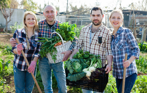 Family of four professional gardeners holding  harvest of vegetables and greens