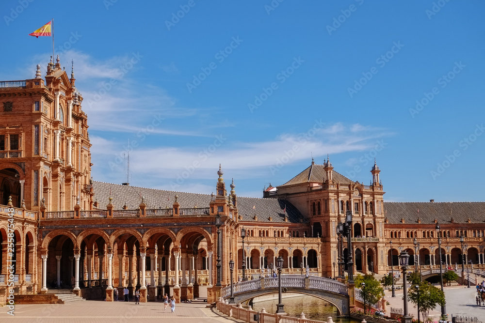 Tourists enjoy sightseeing around famous ancient landmark Plaza de España. Seville Spain.