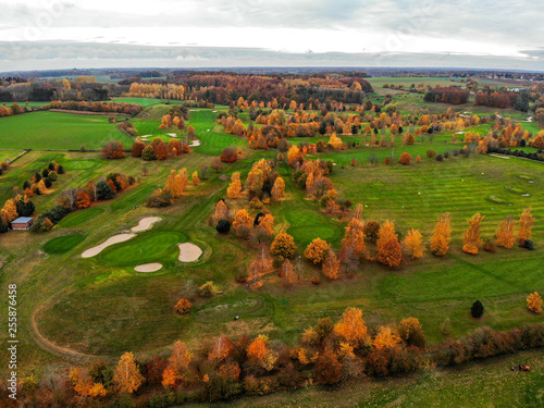 Obraz na płótnie Aerial view of a golf course. Beautiful colorful trees and green course during autumn/winter season in the South of Belgium, Walloon Brabant. w salonie