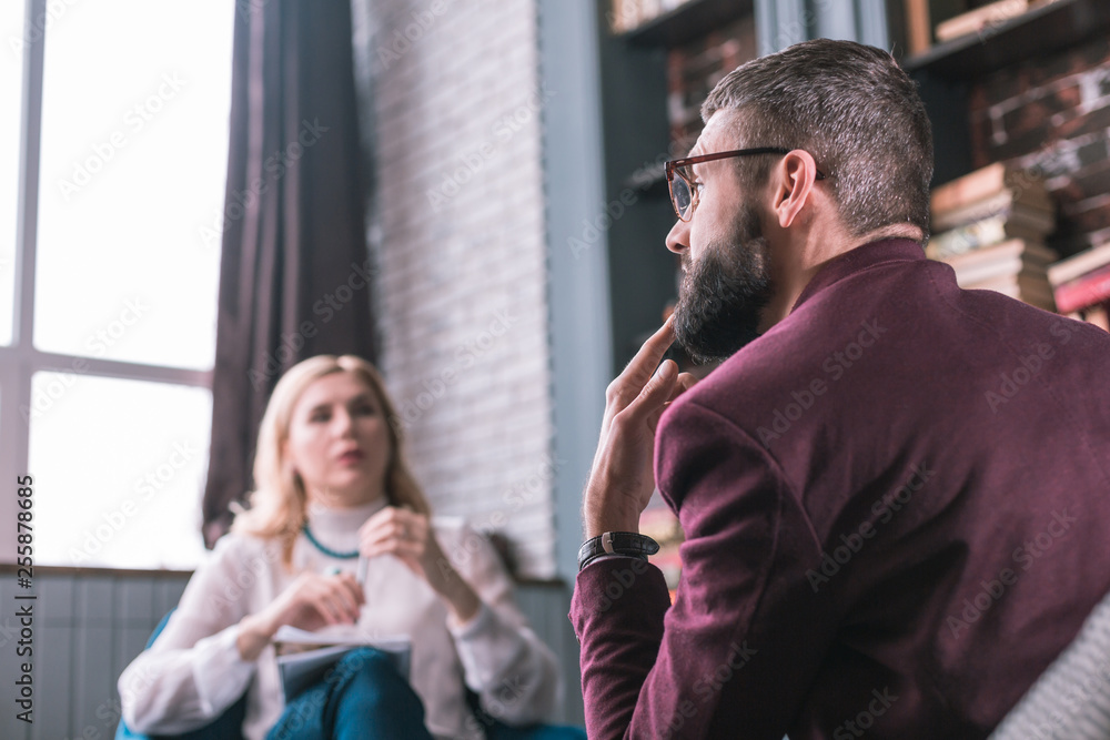 Fototapeta premium Bearded man feeling thoughtful answering questions of psychologist