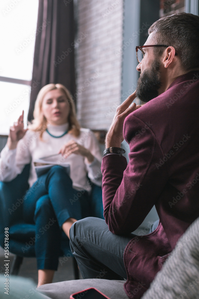 Obraz premium Bearded man feeling worried explaining problems to psychologist