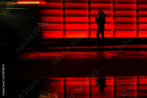 Hjørring, Denmark The red lit-up facade of the Vendsyssel Theater building and a pedestrian at night.