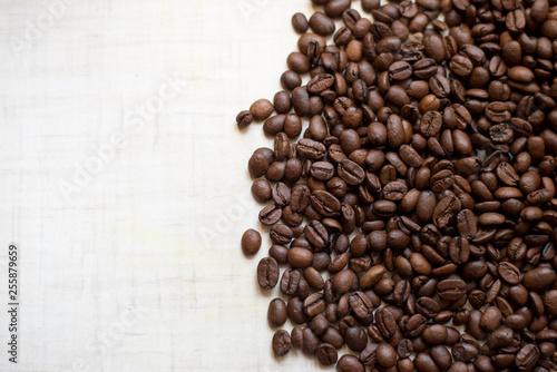 Black coffee grains lie on light wooden table, background image. place for text