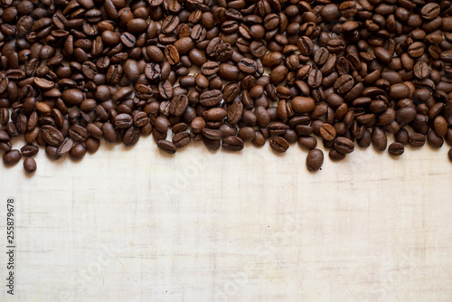 Black coffee grains lie on light wooden table, background image. place for text