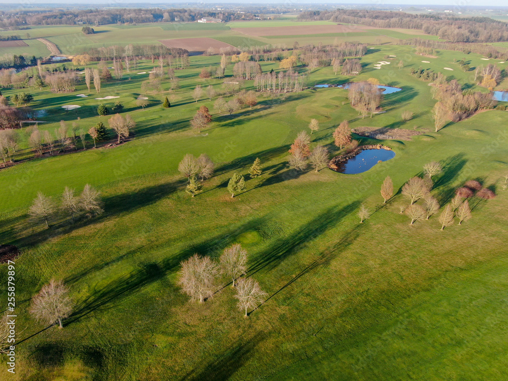 Fototapeta premium Aerial view of a golf course. Beautiful colorful trees and green course during autumn/winter season in the South of Belgium, Walloon Brabant.