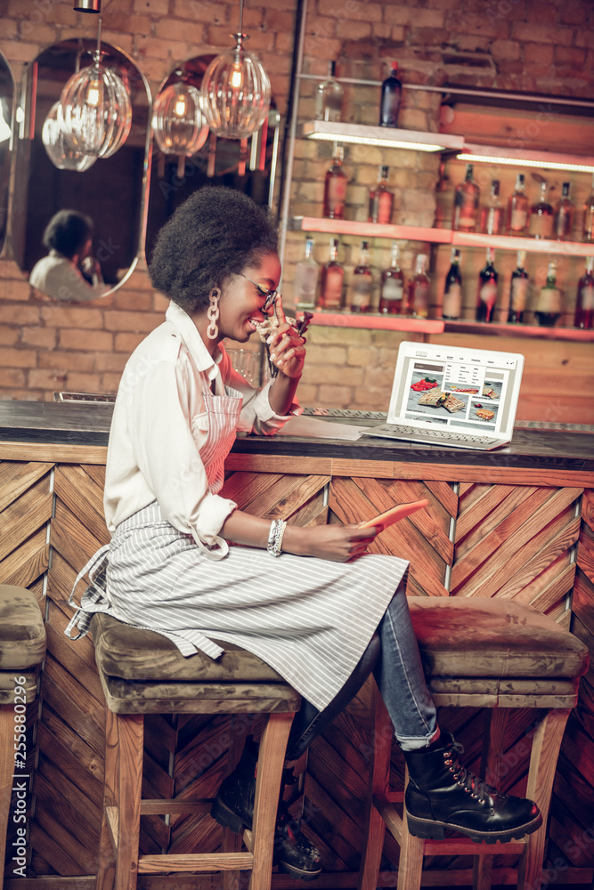 Profile Afro-American waitress sitting in the chair near bar counter Profile Afro-American waitress sitting in the chair near bar counter