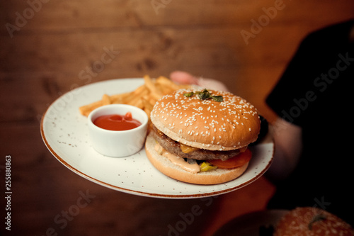 waiter holding a burger on a plate