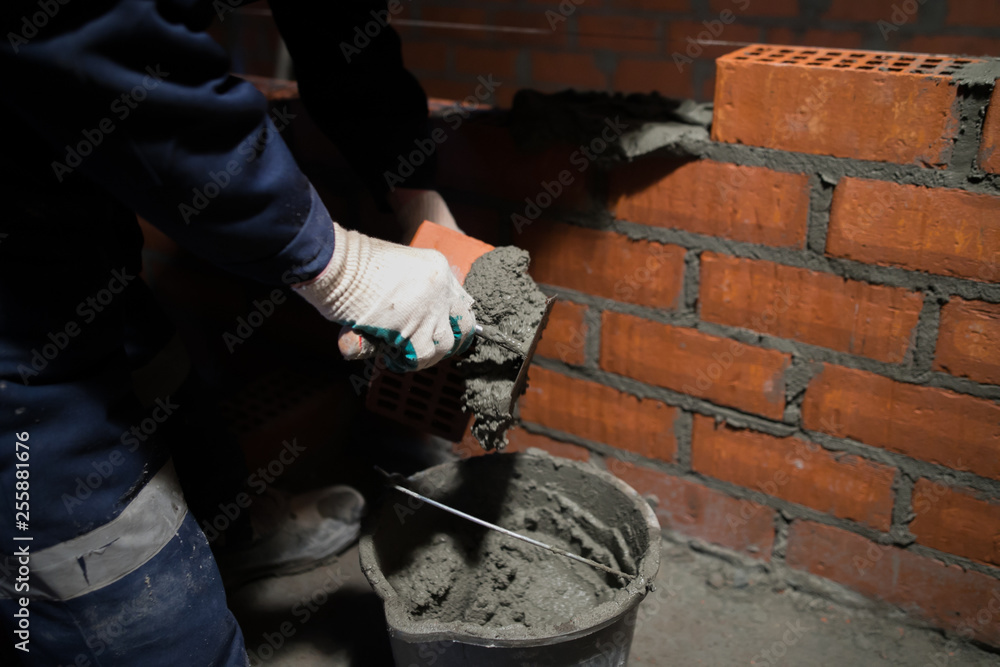 Closeup hand professional construction worker laying bricks in new industrial site Closeup hand professional construction worker laying bricks in new industrial site