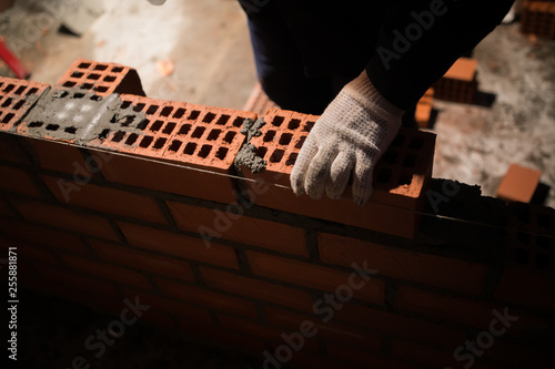 Closeup hand professional construction worker laying bricks in new industrial site