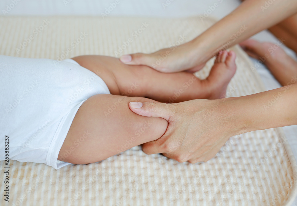 Close-up massaging to leg of infant baby on the bed. Close-up massaging to leg of infant baby on the bed.