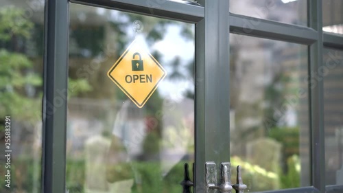 Beautiful asian woman turning the open and closed sign on the door. handheld shot.