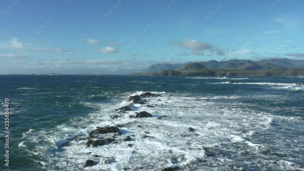 Flying over waves crashing into rocks along the coastline of Vancouver Island on the blue Pacific Ocean. Flying over waves crashing into rocks along the coastline of Vancouver Island on the blue Pacific Ocean.