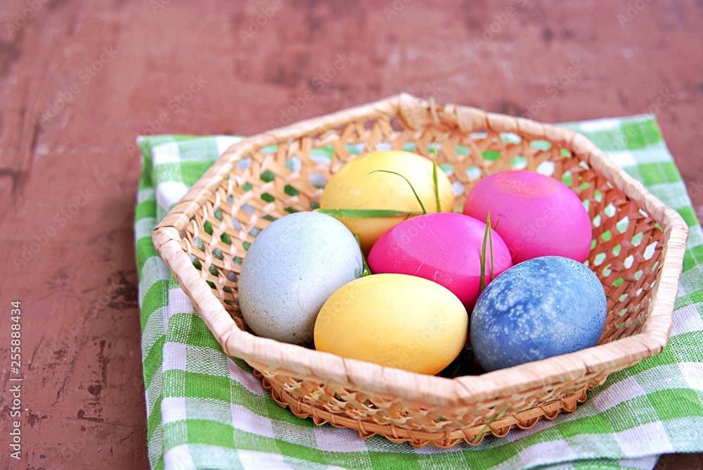 Multi-colored Easter eggs in a wicker basket on a brown background. Selective focus. Happy Easter concept. Multi-colored Easter eggs in a wicker basket on a brown background. Selective focus. Happy Easter concept.