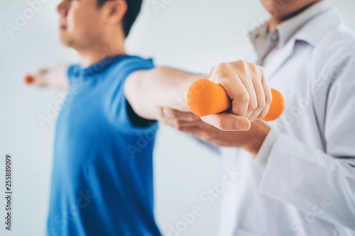 Canvas Print Physiotherapist man giving exercise with dumbbell treatment About Arm and Should