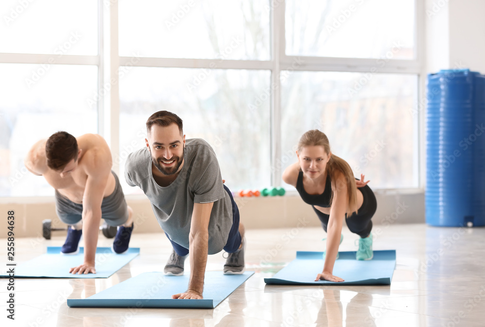Naklejka premium Sporty young people training in gym