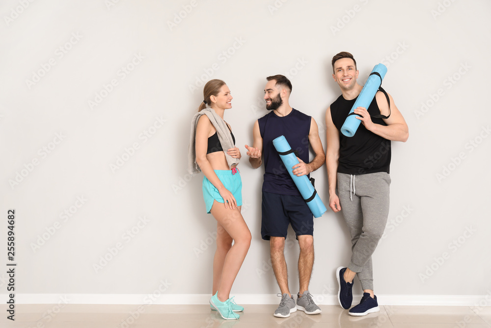 Fototapeta premium Sporty young people near light wall