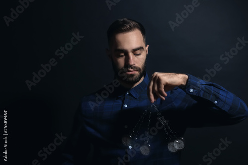Canvas Print Male hypnotist with swinging pendulum on dark background