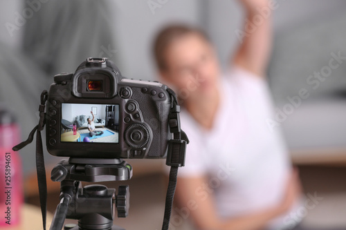 Young female blogger recording sports video at home