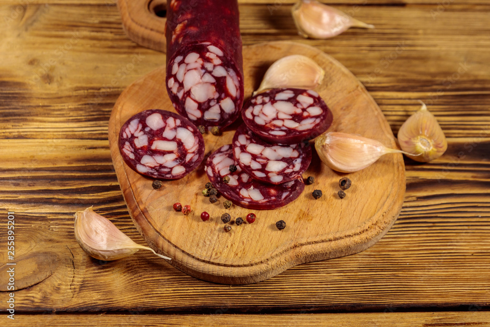 Sliced salami sausage on cutting board on wooden table Sliced salami sausage on cutting board on wooden table