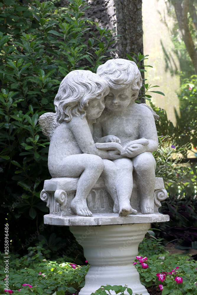 Little cupid statue isolated in the garden Little cupid statue isolated in the garden