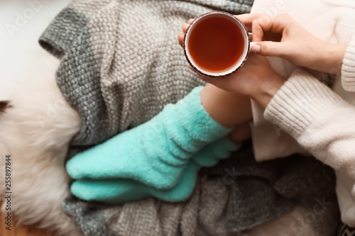 Young woman with cup of hot tea sitting at home