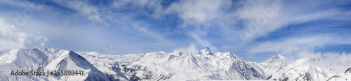 Panorama of winter snowy mountains and blue sky with sunlit clouds © BSANI