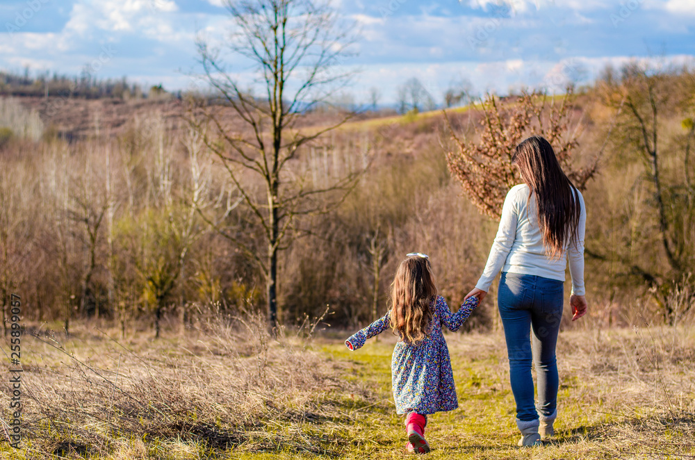 Mother and daughter in nature, holding hands, back view. Mother and daughter in nature, holding hands, back view.