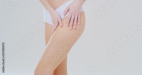 Close up of woman touching gently her perfect body, hips and buttocks without cellulite after curative treatment isolated on a white background.