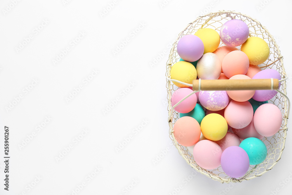 Basket with colorful Easter eggs on white background