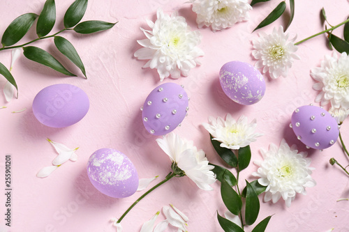 Easter eggs with flowers on color background