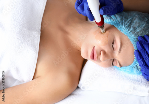 Young woman undergoing procedure of bb glow treatment in beauty salon photo