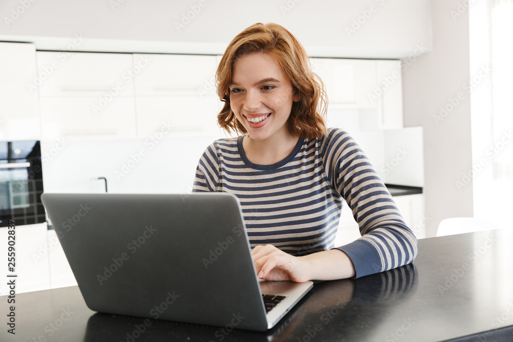 Smiling young woman working on laptop computer Smiling young woman working on laptop computer